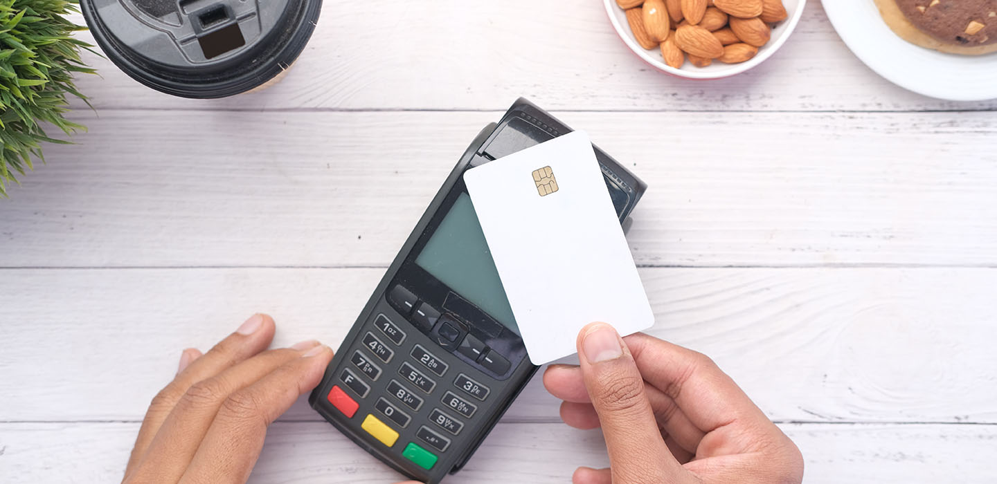 Hands tapping a card on a payment device.