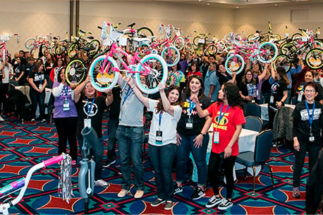 Group photo of employees holding childrens' bikes above their heads