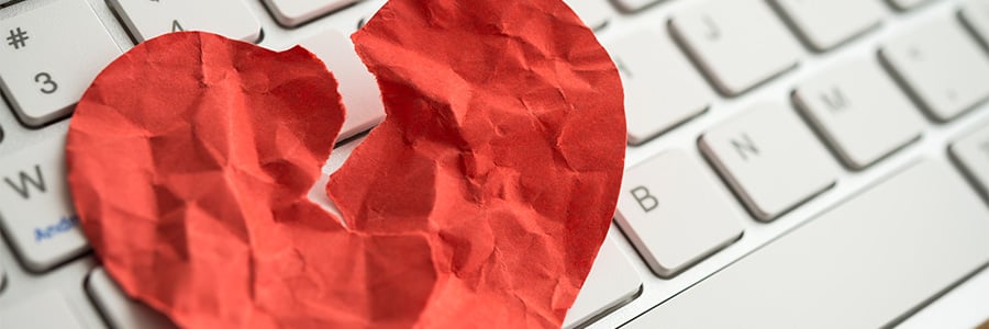Ripped red foil heart on computer keyboard.